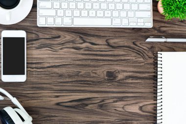 Kahverengi ahşap ofis masası ve çalışma ve dinleme ekipmanları beyaz kulaklıklı üst görünümde ve boşluğu kopyalamak için.