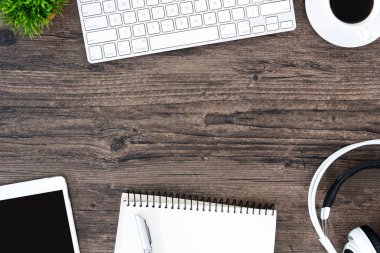 Kahverengi ahşap ofis masası ve çalışma ve dinleme ekipmanları beyaz kulaklıklı üst görünümde ve boşluğu kopyalamak için.