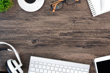 Kahverengi ahşap ofis masası ve çalışma ve dinleme ekipmanları beyaz kulaklıklı üst görünümde ve boşluğu kopyalamak için.