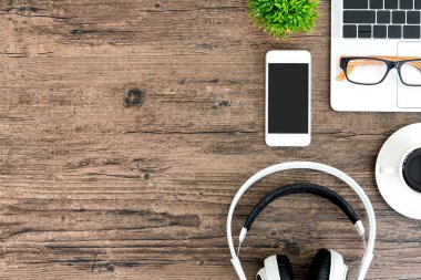 Kahverengi ahşap ofis masası ve çalışma ve dinleme ekipmanları beyaz kulaklıklı üst görünümde ve boşluğu kopyalamak için.