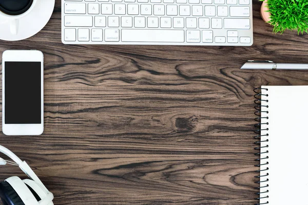 Kahverengi ahşap ofis masası ve çalışma ve dinleme ekipmanları beyaz kulaklıklı üst görünümde ve boşluğu kopyalamak için.