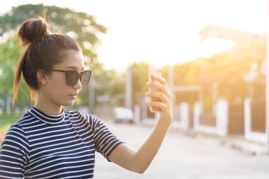 Güzel bir kadının akşamları bahçe parkında ve nehirde günbatımı saatinde telefon ve selfie 'si olur..