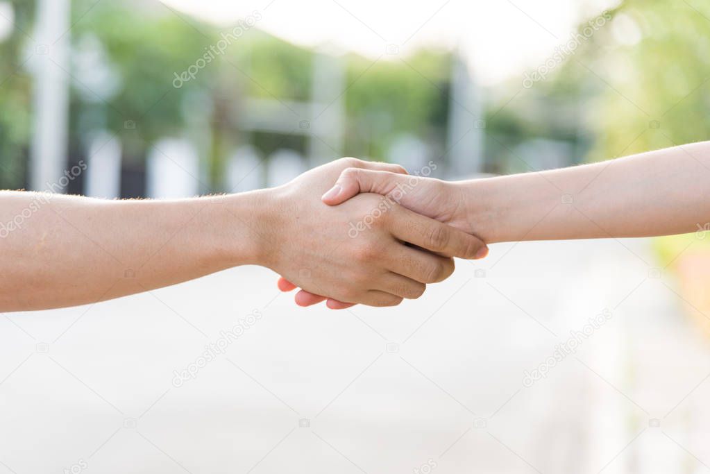 Close up on a asian women holding hands at green and sunset background.