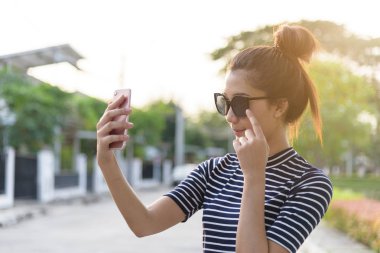 Güzel bir kadının akşamları bahçe parkında ve nehirde günbatımı saatinde telefon ve selfie 'si olur..