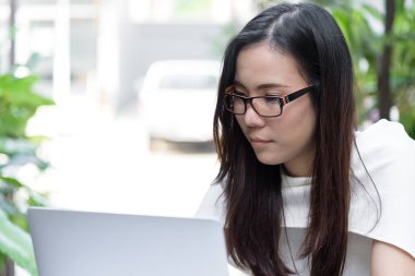 Güzel Asyalı çekici kadın sabahları mutlu ve dinlendirici saatleriyle birlikte iş pazarlaması için dizüstü bilgisayarda çalışıyor ve daktilo kullanıyor..
