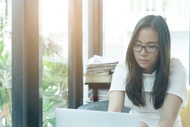 Güzel Asyalı çekici kadın sabahları mutlu ve dinlendirici saatleriyle birlikte iş pazarlaması için dizüstü bilgisayarda çalışıyor ve daktilo kullanıyor..