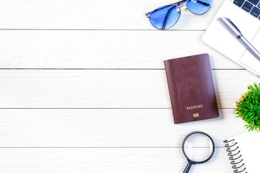 Çalışan ve çalışan masası düz bir manzaradan beyaz ahşap masa üzerinde dizüstü bilgisayar ve pasaportla seyahat etmeye hazırlanıyor ve hayal kuruyor..