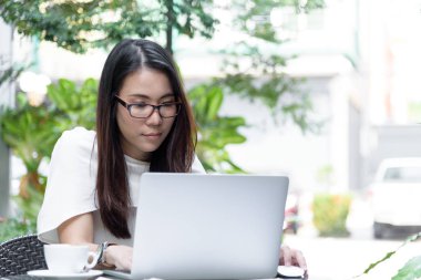 Güzel Asyalı çekici kadın sabahları mutlu ve dinlendirici saatleriyle birlikte iş pazarlaması için dizüstü bilgisayarda çalışıyor ve daktilo kullanıyor..