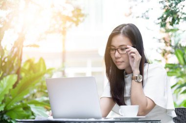 Güzel Asyalı çekici kadın sabahları mutlu ve dinlendirici saatleriyle birlikte iş pazarlaması için dizüstü bilgisayarda çalışıyor ve daktilo kullanıyor..