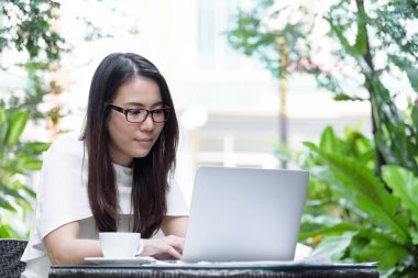 Güzel Asyalı çekici kadın sabahları mutlu ve dinlendirici saatleriyle birlikte iş pazarlaması için dizüstü bilgisayarda çalışıyor ve daktilo kullanıyor..