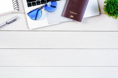 Çalışan ve çalışan masası düz bir manzaradan beyaz ahşap masa üzerinde dizüstü bilgisayar ve pasaportla seyahat etmeye hazırlanıyor ve hayal kuruyor..