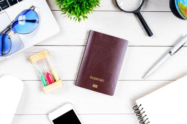 Çalışan ve çalışan masası düz bir manzaradan beyaz ahşap masa üzerinde dizüstü bilgisayar ve pasaportla seyahat etmeye hazırlanıyor ve hayal kuruyor..
