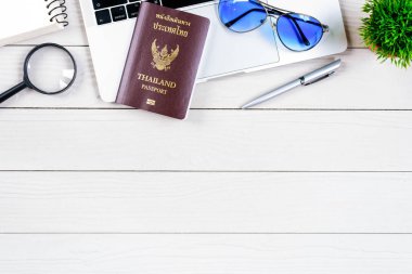 Taylandlı işçi ve çalışan masası, düz bir manzaradan beyaz ahşap masaya dizilmiş dizüstü bilgisayar, Tayland ve pasaportla seyahat etmeye ve seyahat etmeye hazırlanıyor..