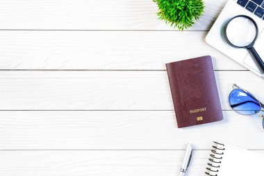 Çalışan ve çalışan masası düz bir manzaradan beyaz ahşap masa üzerinde dizüstü bilgisayar ve pasaportla seyahat etmeye hazırlanıyor ve hayal kuruyor..