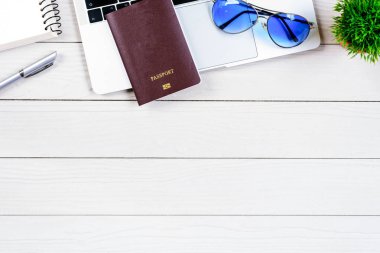 Çalışan ve çalışan masası düz bir manzaradan beyaz ahşap masa üzerinde dizüstü bilgisayar ve pasaportla seyahat etmeye hazırlanıyor ve hayal kuruyor..