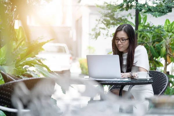 Güzel Asyalı çekici kadın sabahları mutlu ve dinlendirici saatleriyle birlikte iş pazarlaması için dizüstü bilgisayarda çalışıyor ve daktilo kullanıyor..