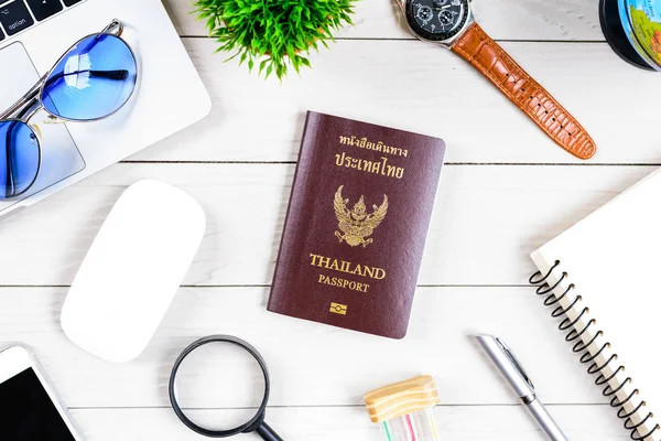 The thai people worker and employee desk has trip dreaming and preparing to journey and travel around the world with laptop and thailand passport on white wood table from flat lay top view.