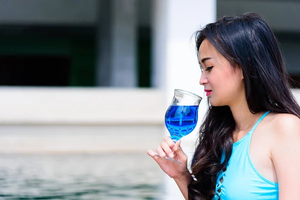 Sexy asian woman has drinking blue wine in the evening and sunset time with relaxing on vacation and holiday.