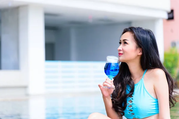 Sexy asian woman has drinking blue wine in the evening and sunset time with relaxing on vacation and holiday.