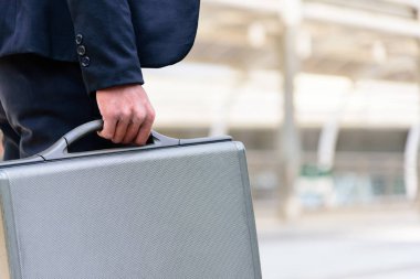 Asyalı işadamının elinde siyah bir çanta var..