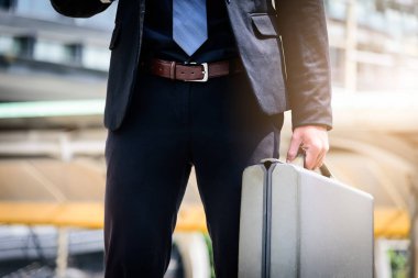 Asyalı işadamının elinde siyah bir çanta var..
