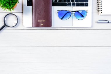Çalışan ve çalışan masası düz bir manzaradan beyaz ahşap masa üzerinde dizüstü bilgisayar ve pasaportla seyahat etmeye hazırlanıyor ve hayal kuruyor..