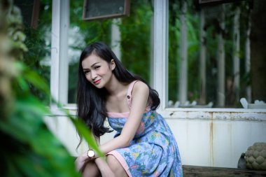 Asyalı güzel kız, Tayland 'ın Nakhon Pathom bölgesindeki Küçük Ağaç Bahçesi Kafesi' nde mutlu ve gülümseyerek dinleniyor..