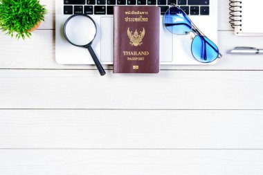 Taylandlı işçi ve çalışan masası, düz bir manzaradan beyaz ahşap masaya dizilmiş dizüstü bilgisayar, Tayland ve pasaportla seyahat etmeye ve seyahat etmeye hazırlanıyor..
