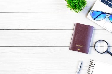 Çalışan ve çalışan masası düz bir manzaradan beyaz ahşap masa üzerinde dizüstü bilgisayar ve pasaportla seyahat etmeye hazırlanıyor ve hayal kuruyor..