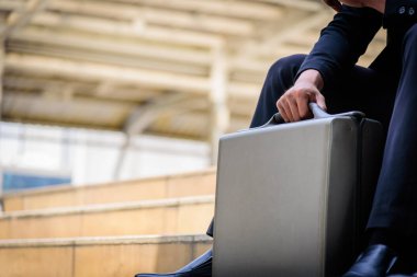 Asyalı işadamının elinde siyah bir çanta var..