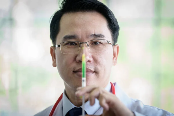 Médico asiático profesional con jeringa verde y fractura. — Foto de Stock
