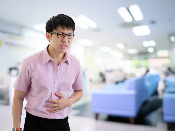 El empresario asiático se ha puesto de pie con el estomachache en el hospital con. — Foto de Stock