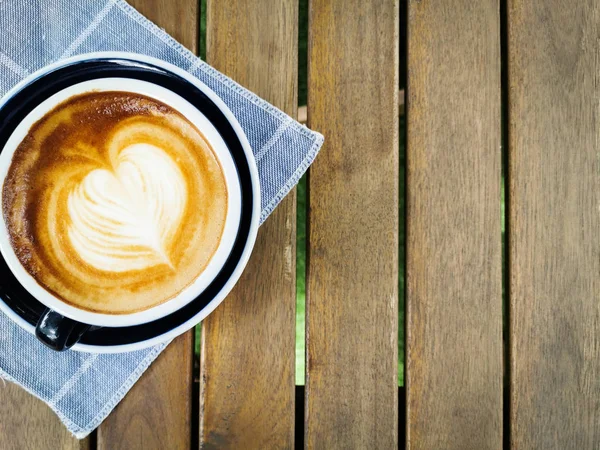 Una taza de café con hermoso arte latte en la mesa de madera backgroun. — Foto de Stock