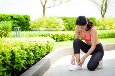 Güzel kadın koşucu bahçede beyaz ayakkabı bağcığı bağlamak zorunda..