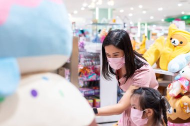 Editör: Merkez Bangna Bangkok City, Tayland, 6 Haziran 2020. Asyalı bir kadın ve kız, pembe maske ve sosyal mesafeyle kilidi açtıktan sonra oyuncakçıdan alışveriş yapıyor..