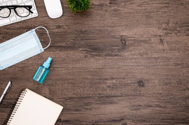 COVID-19 'u koruyacak ekipman, mavi maske ve el temizleme jeli, evden işe hazırlanmak için ahşap masa üzerinde izole edilmiş..