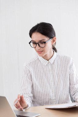 Ofiste gülümseyen ve mutlu bir şekilde çalışan gözlüklü bir iş kadını..