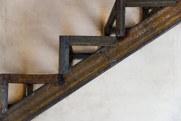 Gri beton zemin üzerine paslı kaynaklı metal merdiven boşluğu