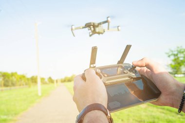 Uçan quadcopter dron eylem kamera ile hava altında mavi gökyüzü ve elinde uzaktan kumanda