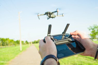 Uçan quadcopter dron eylem kamera ile hava altında mavi gökyüzü ve elinde uzaktan kumanda