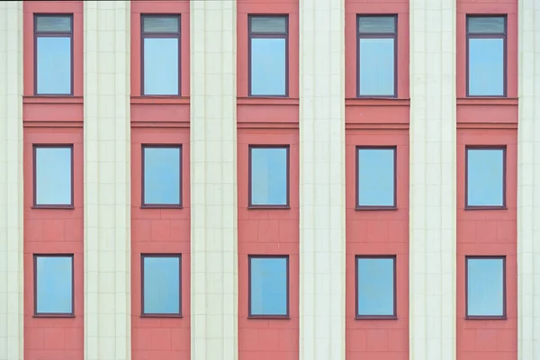 Цветная красная фасадная стена с колоннами и текстурой окон — стоковое фото