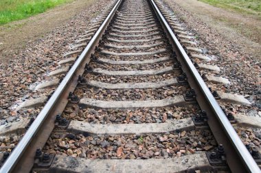 Paslı demiryolu gri bulutlu gökyüzü altında ormandaki taşlarla