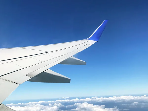 Widok z samolotu iluminator na skrzydle, zachmurzone niebo. — Zdjęcie stockowe