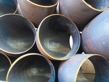 Endüstriyel metal boruların beton zeminde doğru açıyla çekilmesi. 90 derecelik açıyla geniş çaplı paslı metal borular. Yüksek kalite fotoğraf