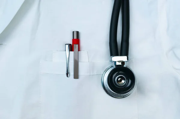 Svarta och röda pennor i den främre fickan på läkarna vit rock med stetoskop fonoskop — Stockfoto