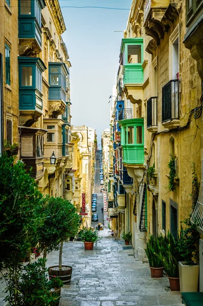 Landmark of narrow hilly road with colourful balcony in the ancient city of Valletta, Malta