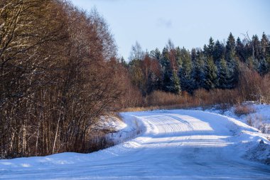 Kırsal kesimde karla kaplı yolda parlayan güneş