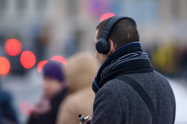 05.02.2019.; Riga; Letonya. Genç adam kafasına, kulaklıklarla otobüs durağında bekleyen otobüs ise Sigara.