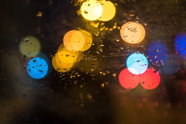 Ön plan üzerinde odaklanın. Araba camına yağmur damlaları. Arka plan trafik ve şehir ışıkları.