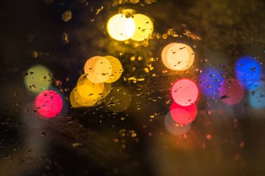 Ön plan üzerinde odaklanın. Araba camına yağmur damlaları. Arka plan trafik ve şehir ışıkları.